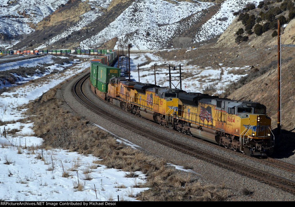 UP 8664, 9021, 7781 (SD70ACE, SD70ACE, C45ACCTE) lead an eastbound stack train approaching the Echo Rd. OHB in Emory, Utah. February 19, 2022 {Winter Echofest}
